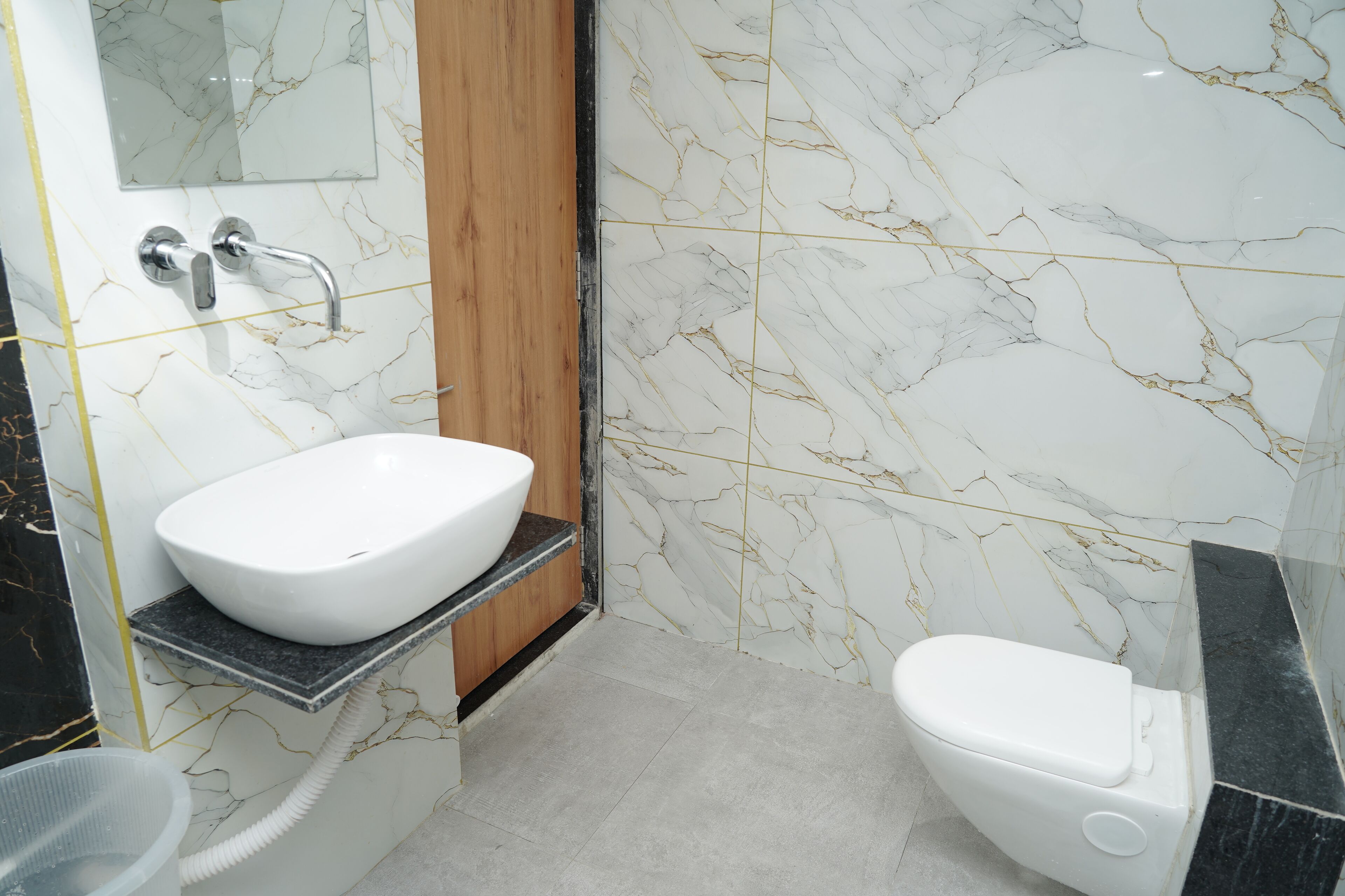A bathroom with a white sink, a toilet, and marble walls.
