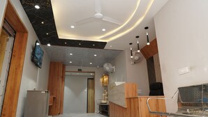 Un'area reception con una scrivania in legno, una zona con posti a sedere, una ventola a soffitto e un punto luce fissato al muro.