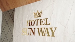 Un muro di marmo con la scritta “HOTEL SUN WAY” e un simbolo a forma di corona.