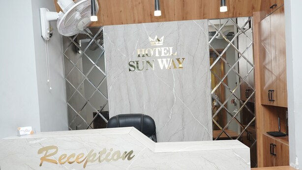 Una reception con piano in marmo e base in legno, una ventola e un cartello con la scritta 'HOTEL SUNWAY'.
