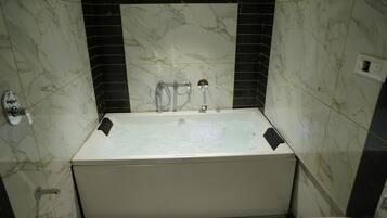 A bathroom with a bathtub, a toilet, and a shower area.