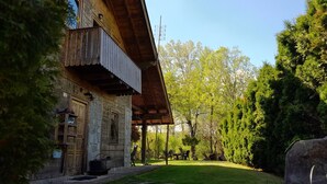 A rustic wooden house with a stone facade, a balcony, and a well-maintained lawn.