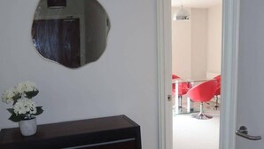 Una habitación con un aparador de madera oscura, un espejo redondo y una planta en maceta.
