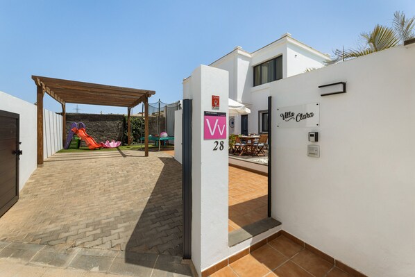 A villa with a paved patio, a children's play area with slides, and a covered seating area. - Casa Clara by Escapehome (Playa Blanca)
