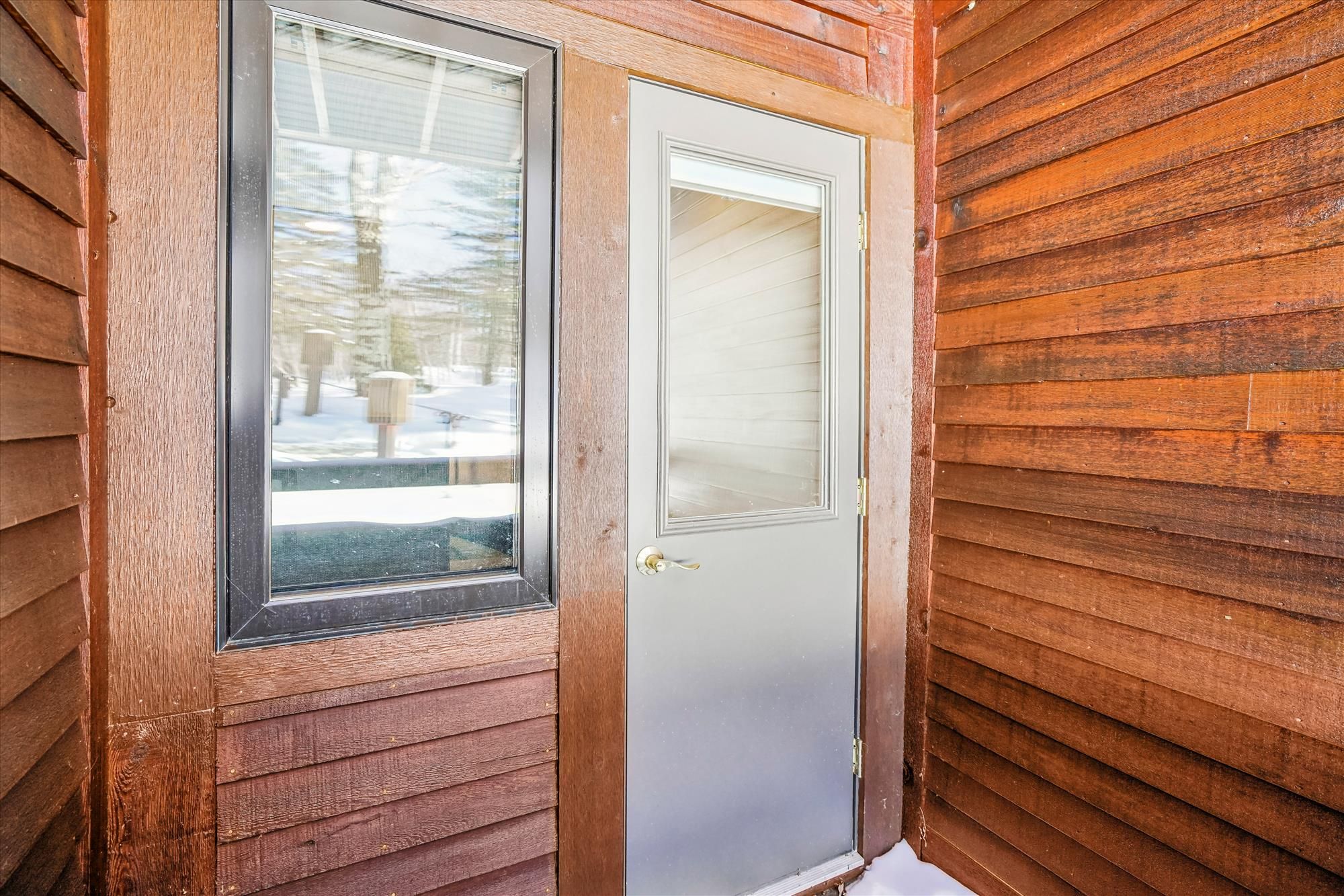 A wooden door with a window and a door handle.