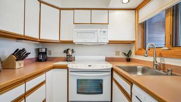 Compact Kitchen with Mountain Condo Charm - The fully equipped kitchen offers full-size appliances, generous counter space, and everything you need to prepare meals during your stay.