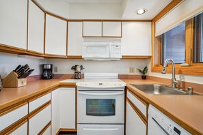 Compact Kitchen with Mountain Condo Charm - The fully equipped kitchen offers full-size appliances, generous counter space, and everything you need to prepare meals during your stay.