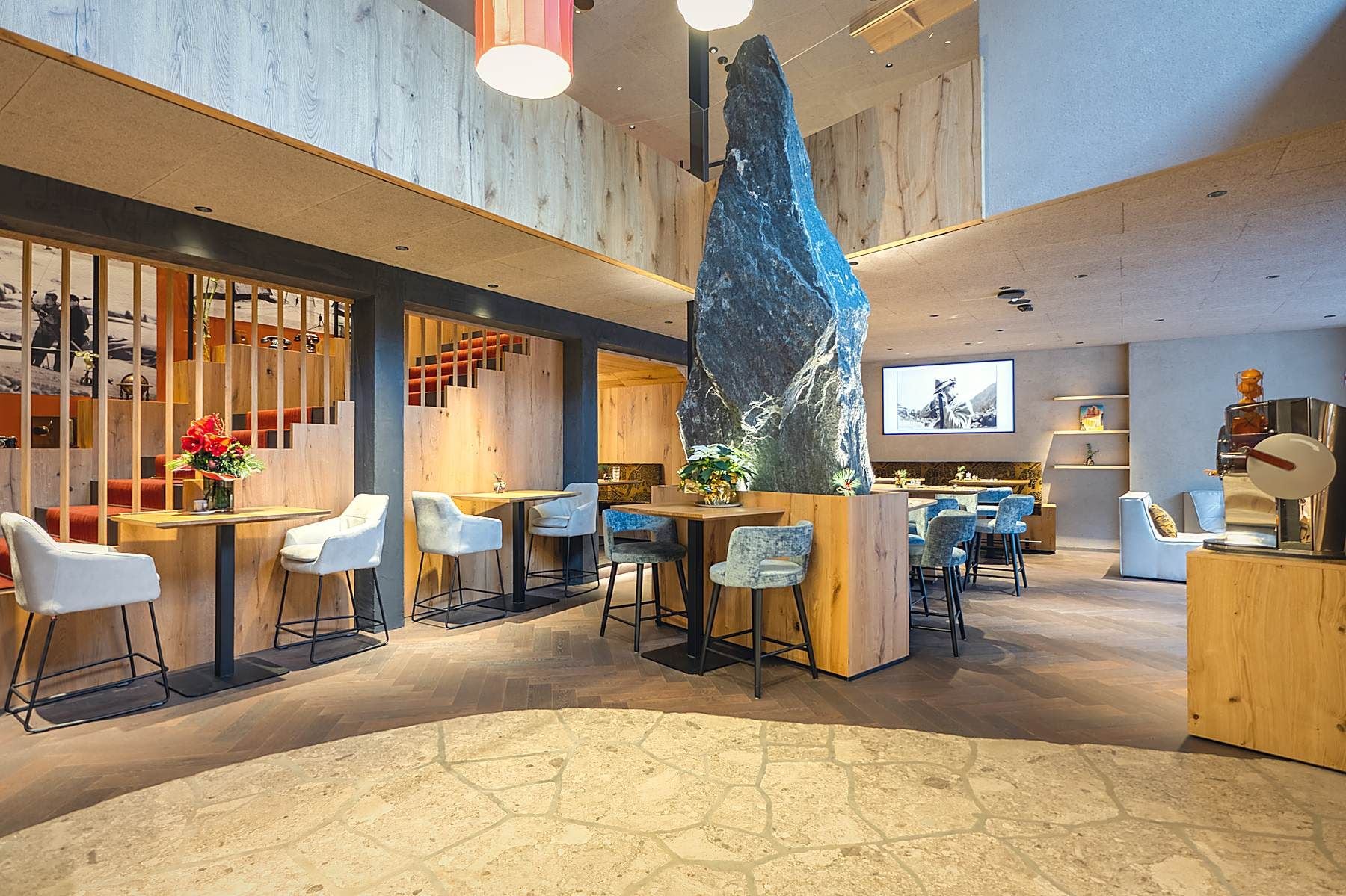 Un intérieur moderne avec un élément central en roche, des espaces de détente et un bar.