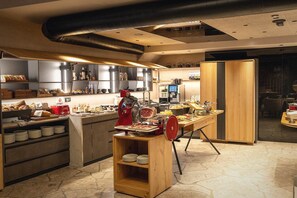 A modern kitchen with a central island, various appliances, and a seating area. - La Tambra - Hotel Lodge (Santa Cristina Val Gardena)