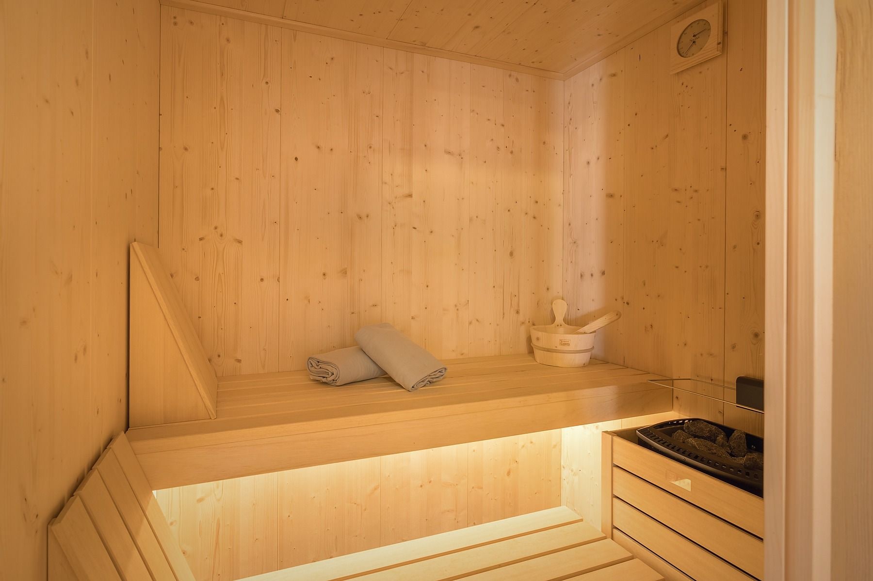 Eine Holzsauna mit einer Bank, einem Handtuch und einem Eimer.