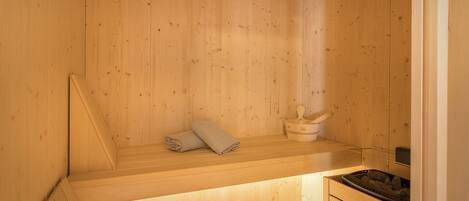 Eine Holzsauna mit einer Bank, einem Handtuch und einem Eimer.