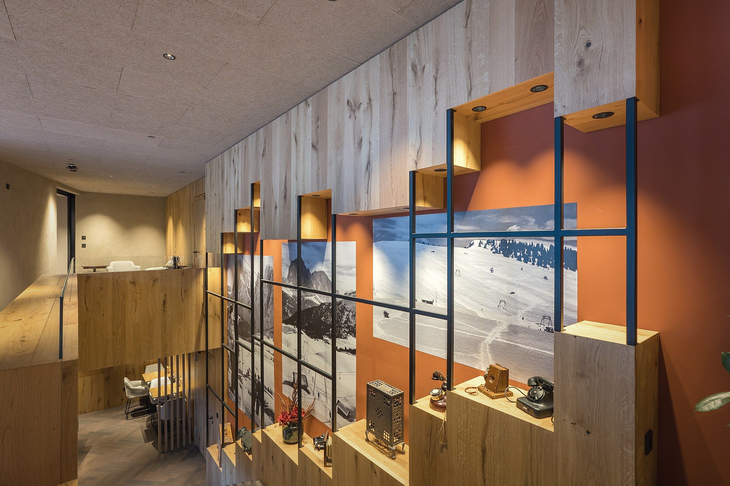 Un interior moderno con paneles de madera, un comedor y un amplio ventanal con vistas a una montaña nevada.
