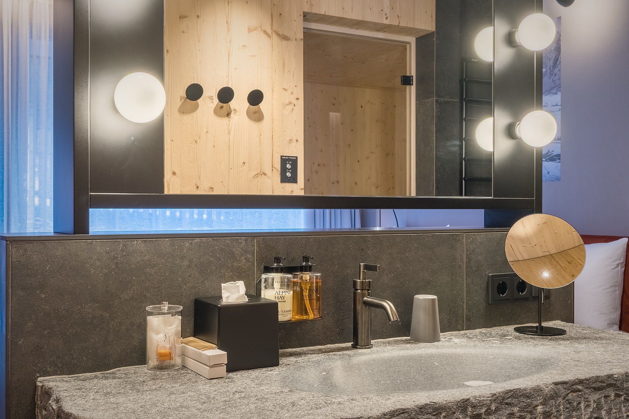 A bathroom with a large mirror, vanity, and toiletries.