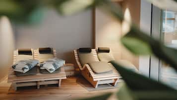 Zwei Holz-Loungestühle mit Kissen, platziert in einem Raum mit Holzboden und einem großen Fenster.