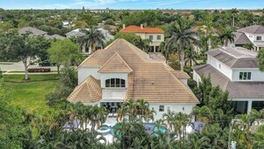 A large house with a prominent front porch, a swimming pool, and a well-maintained lawn.