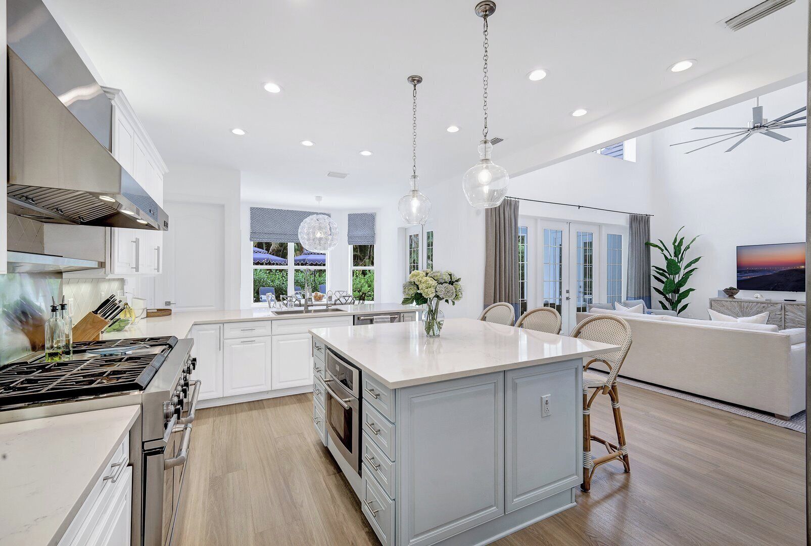 A modern kitchen with a central island, white cabinetry, and a dining area with wicker chairs.