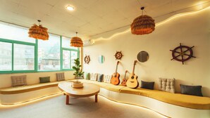 A modern interior with a curved sofa, a round table, and wall-mounted guitars. - Hostel De Offlanders Rishikesh • Stay • Connect • Explore (Rishikesh)