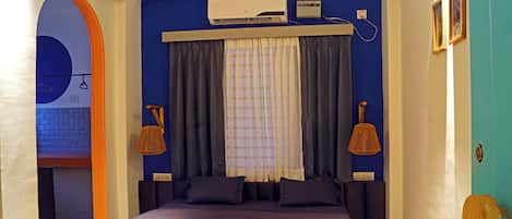 Un dormitorio con cama, cortinas, aire acondicionado y una lámpara de pared.