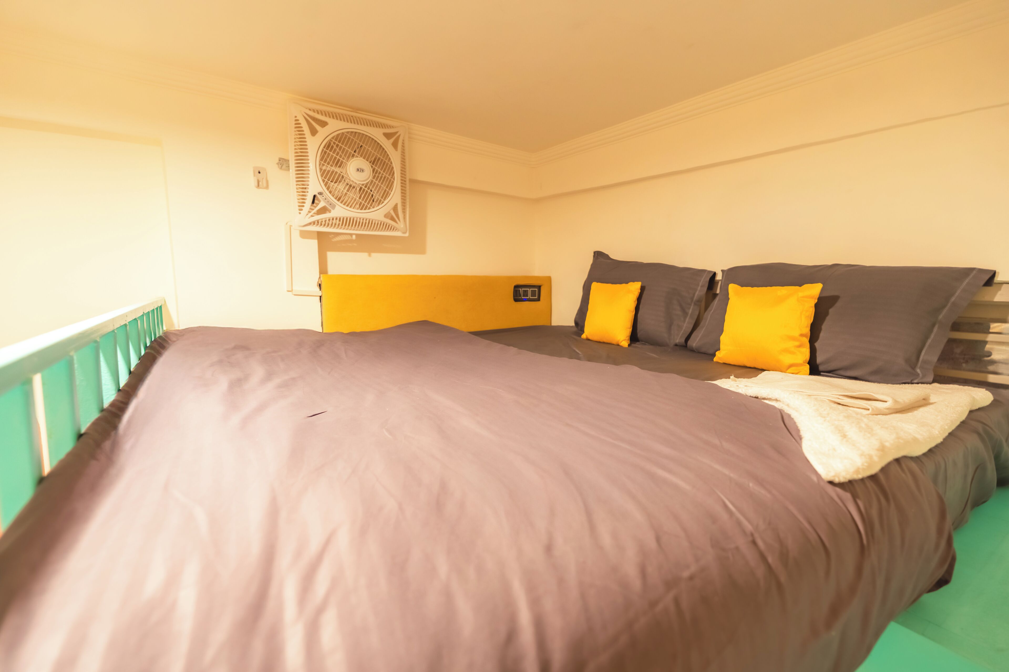 A bed with a headboard, a bedside table, and a wall-mounted fan.