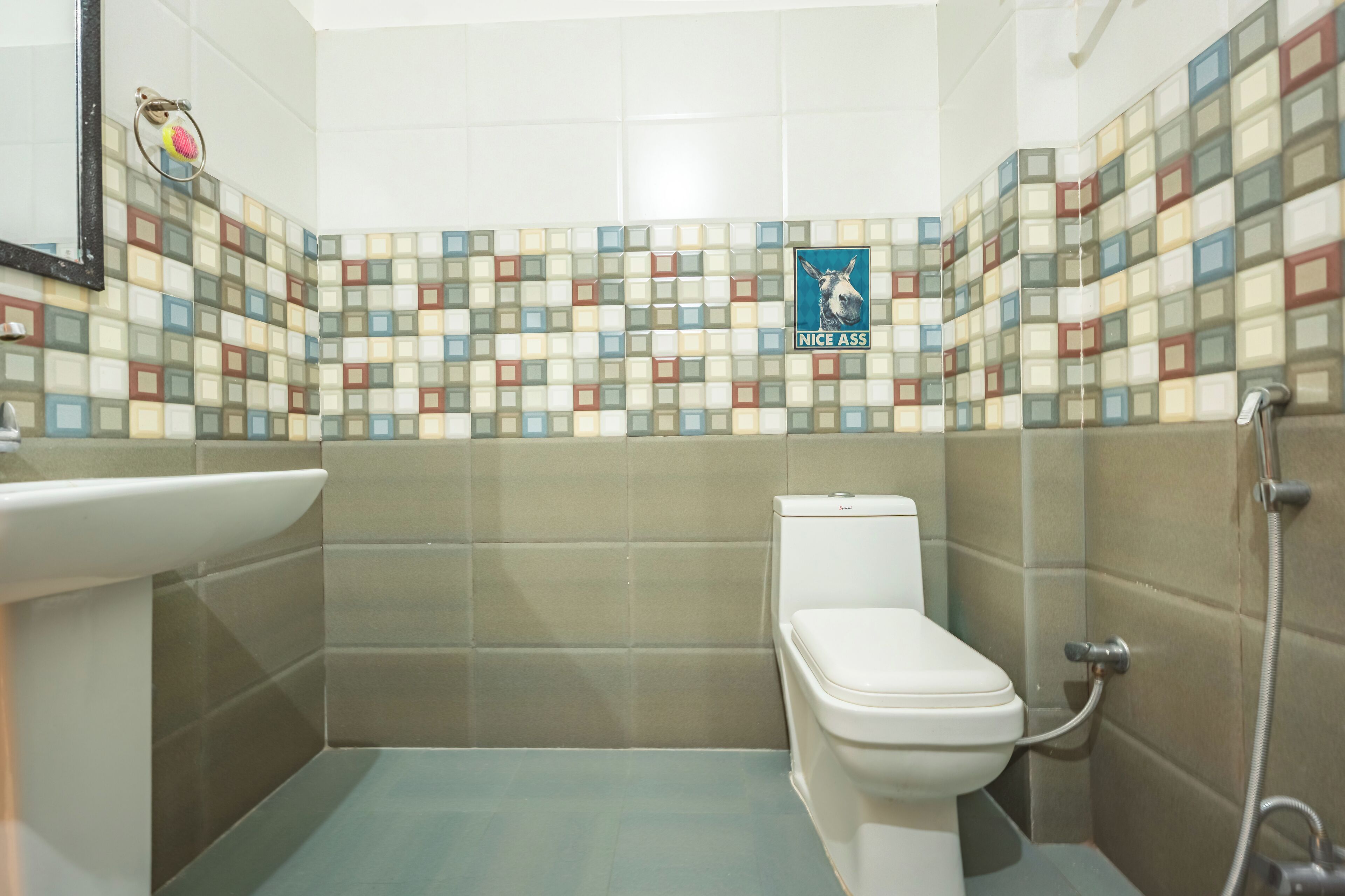 A bathroom with a tiled wall, a toilet, a sink, and a shower.