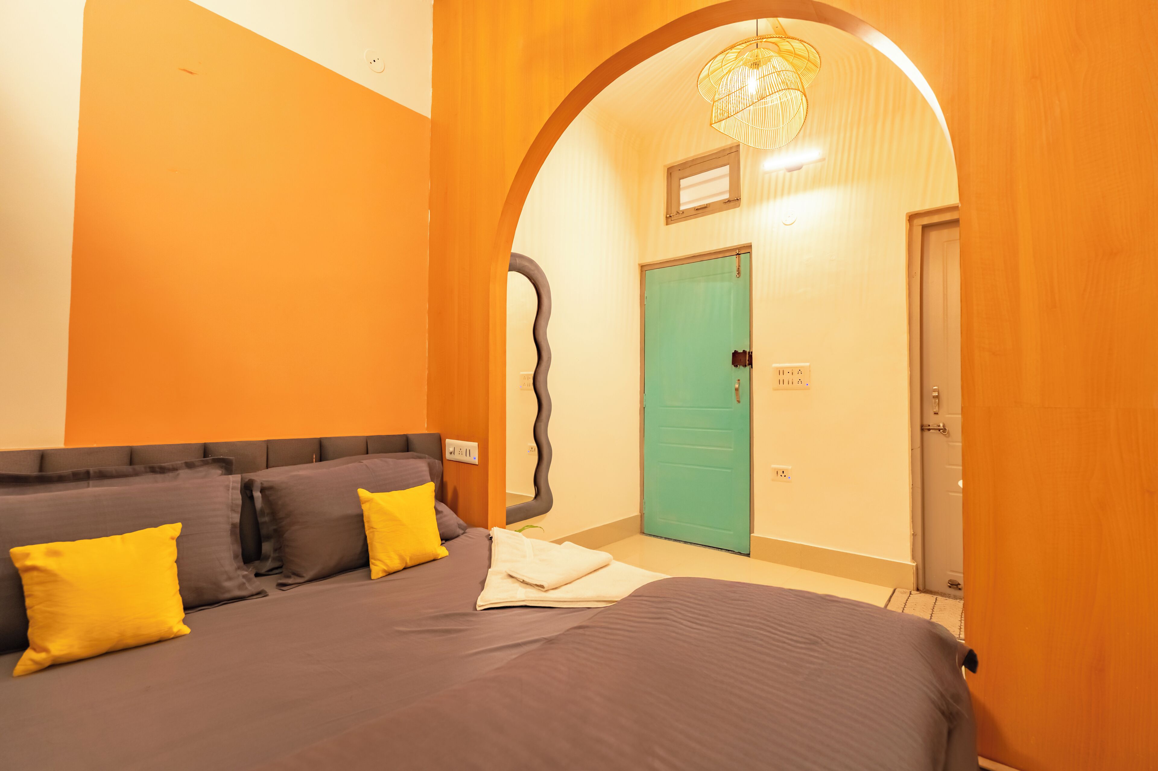 Un dormitorio con cama, almohadas y un espejo curvo peculiar.