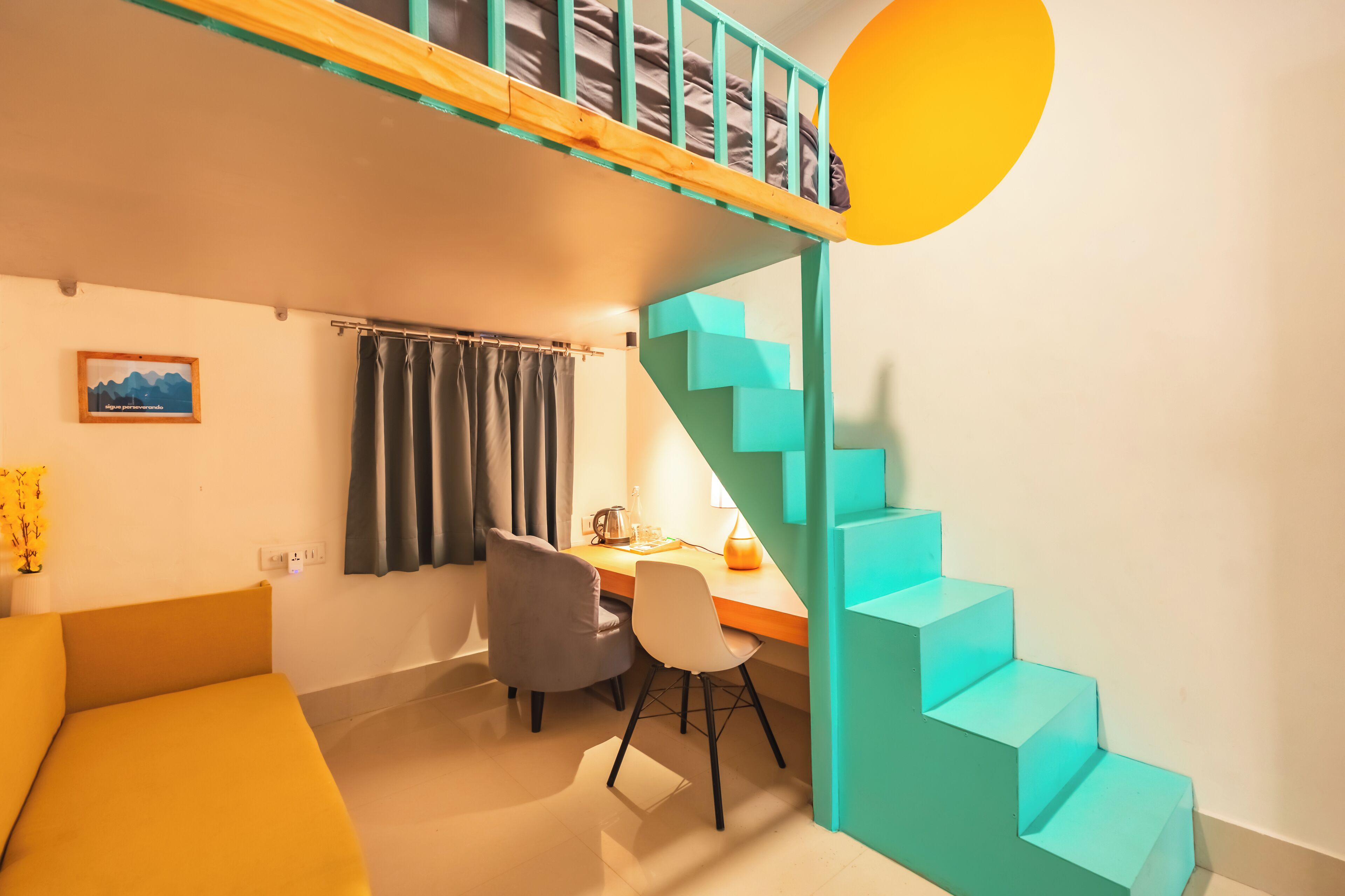 Habitación pequeña con literas, un escritorio y una escalera.