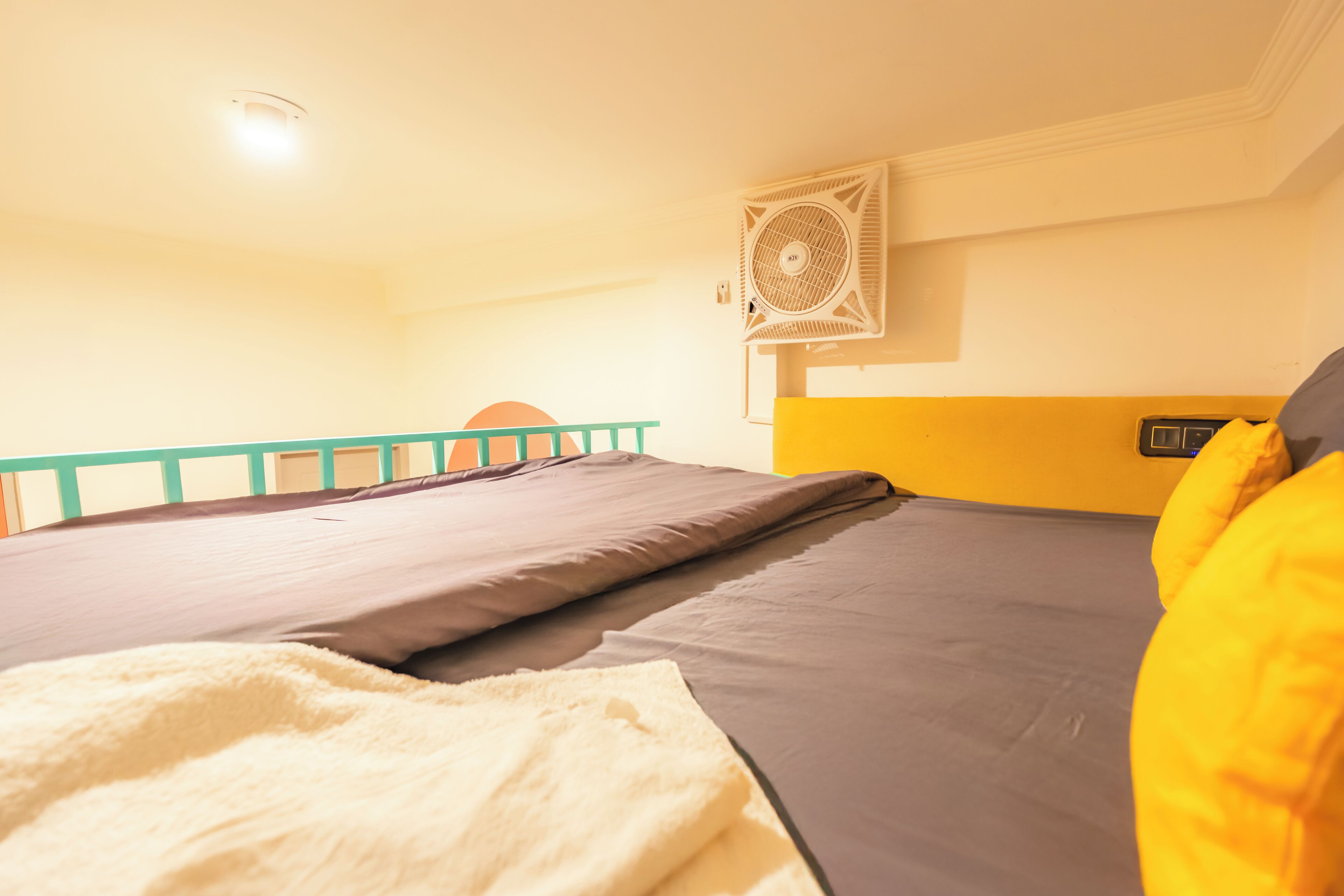 A room with a bed, a fan, and a window.
