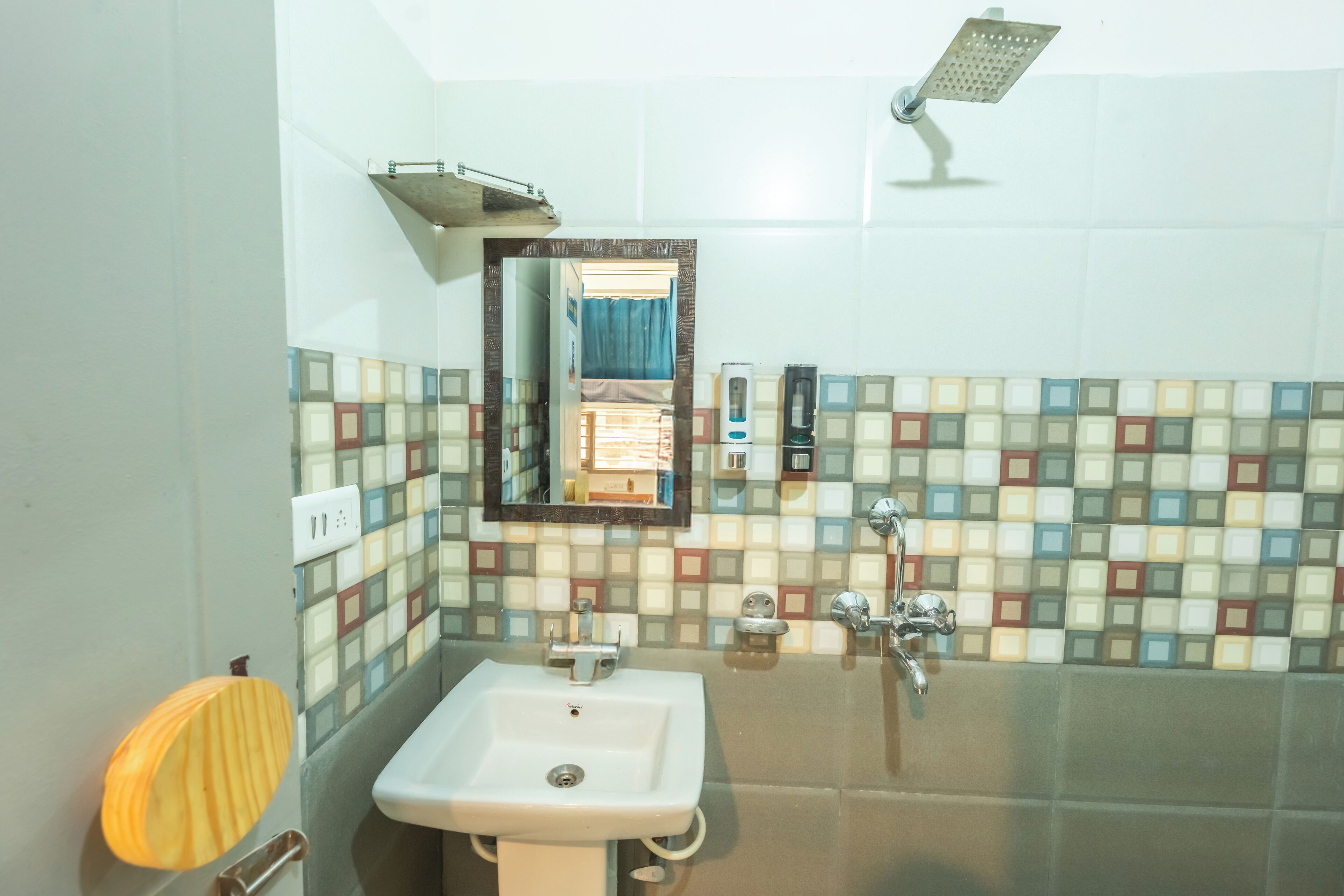 Un baño con lavamanos, espejo, ducha y paredes con azulejos.