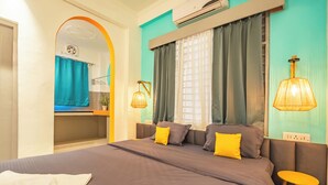 A modern hotel room with a large bed, a small table, and a mirror with a decorative arch. - Hostel De Offlanders Rishikesh • Stay • Connect • Explore (Rishikesh)
