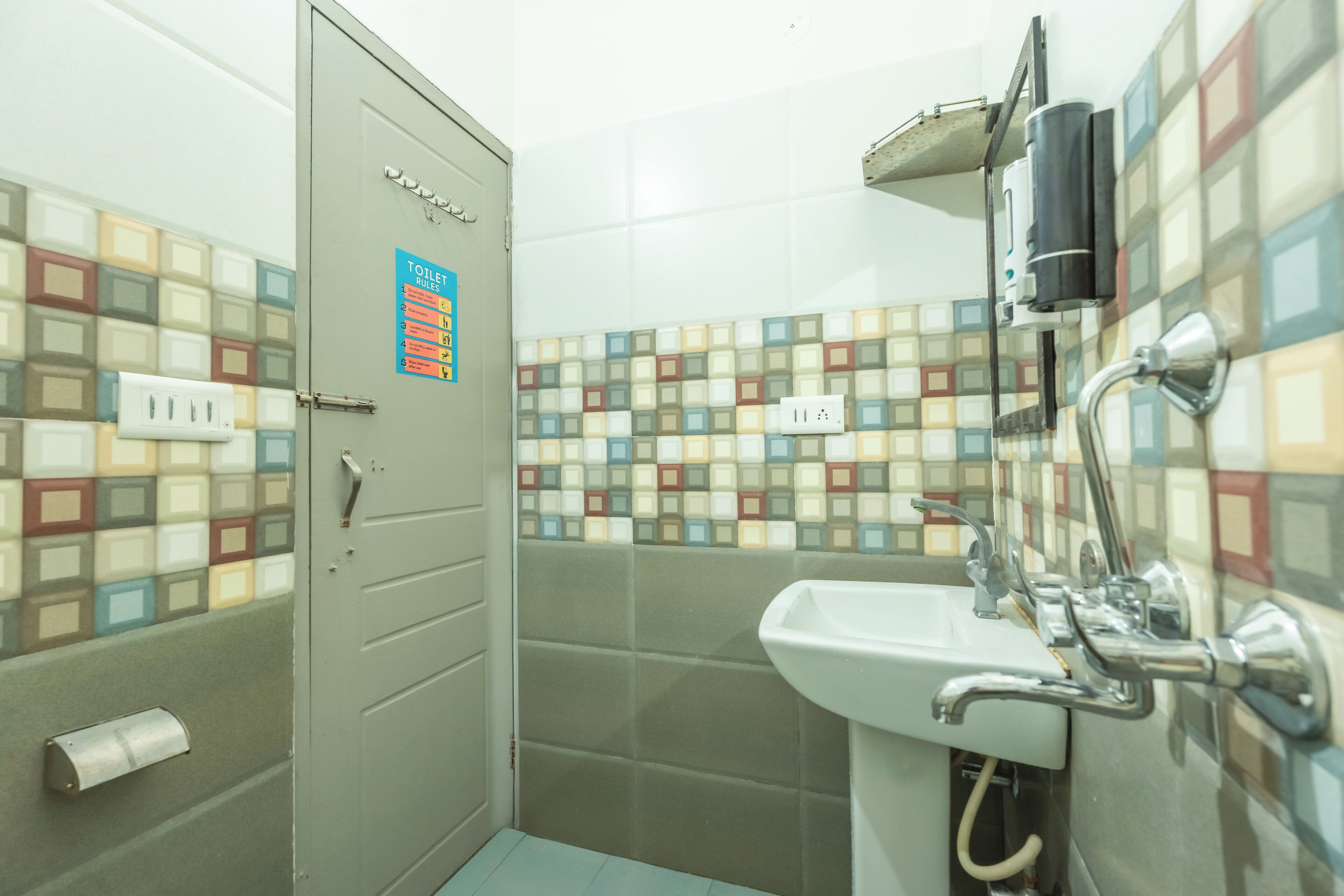 A bathroom with a tiled wall, a sink, and a toilet.