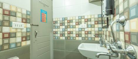 A bathroom with a tiled wall, a sink, and a toilet.