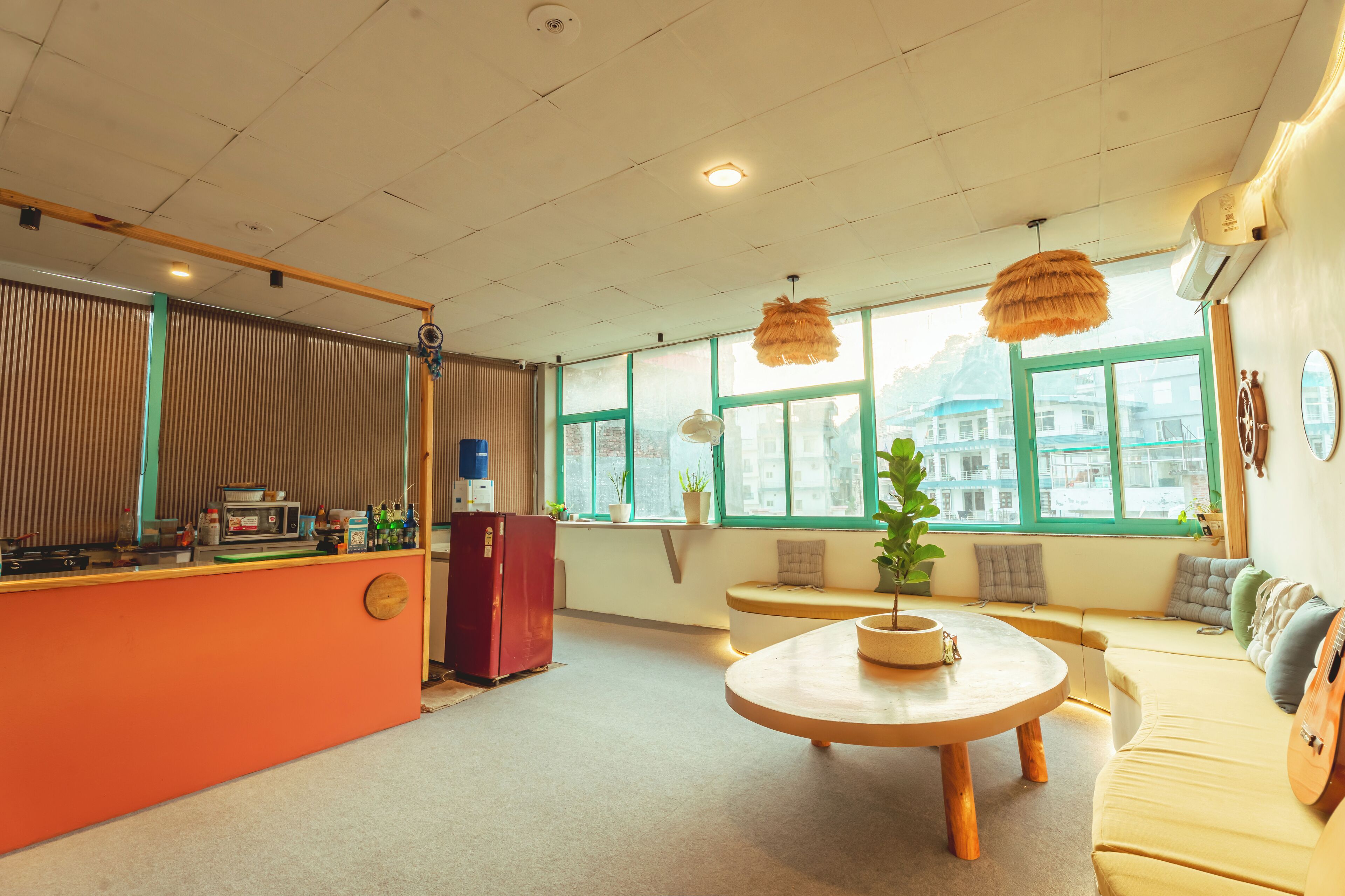 A modern interior with a wooden reception desk, a round wooden table, a sofa, and a window with a view of buildings.