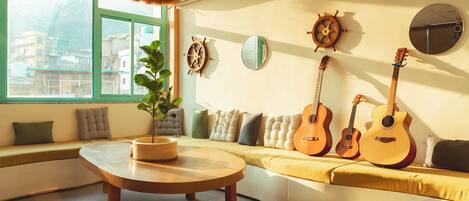 A cozy room with a curved sofa, a round coffee table, and three guitars against the wall.
