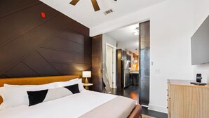 A hotel room with a large bed, a wooden headboard, a bedside table with a lamp, and a wooden dresser. - Neon Daes Amazing Location Near Vandy & Centennial Park, 10 min to Broadway (Nashville)