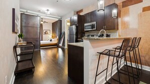 A modern kitchen with dark wood cabinets, a stainless steel microwave, and a bar area with metal stools. - Neon Daes Amazing Location Near Vandy & Centennial Park, 10 min to Broadway (Nashville)