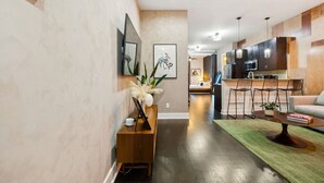 A modern living room with a wooden coffee table, a sofa, and a kitchen area with dark cabinets and a microwave. - Neon Daes Amazing Location Near Vandy & Centennial Park, 10 min to Broadway (Nashville)