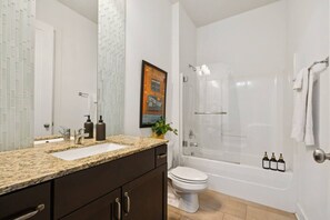 Un baño moderno con encimera de granito, inodoro, bañera y cabina de ducha.