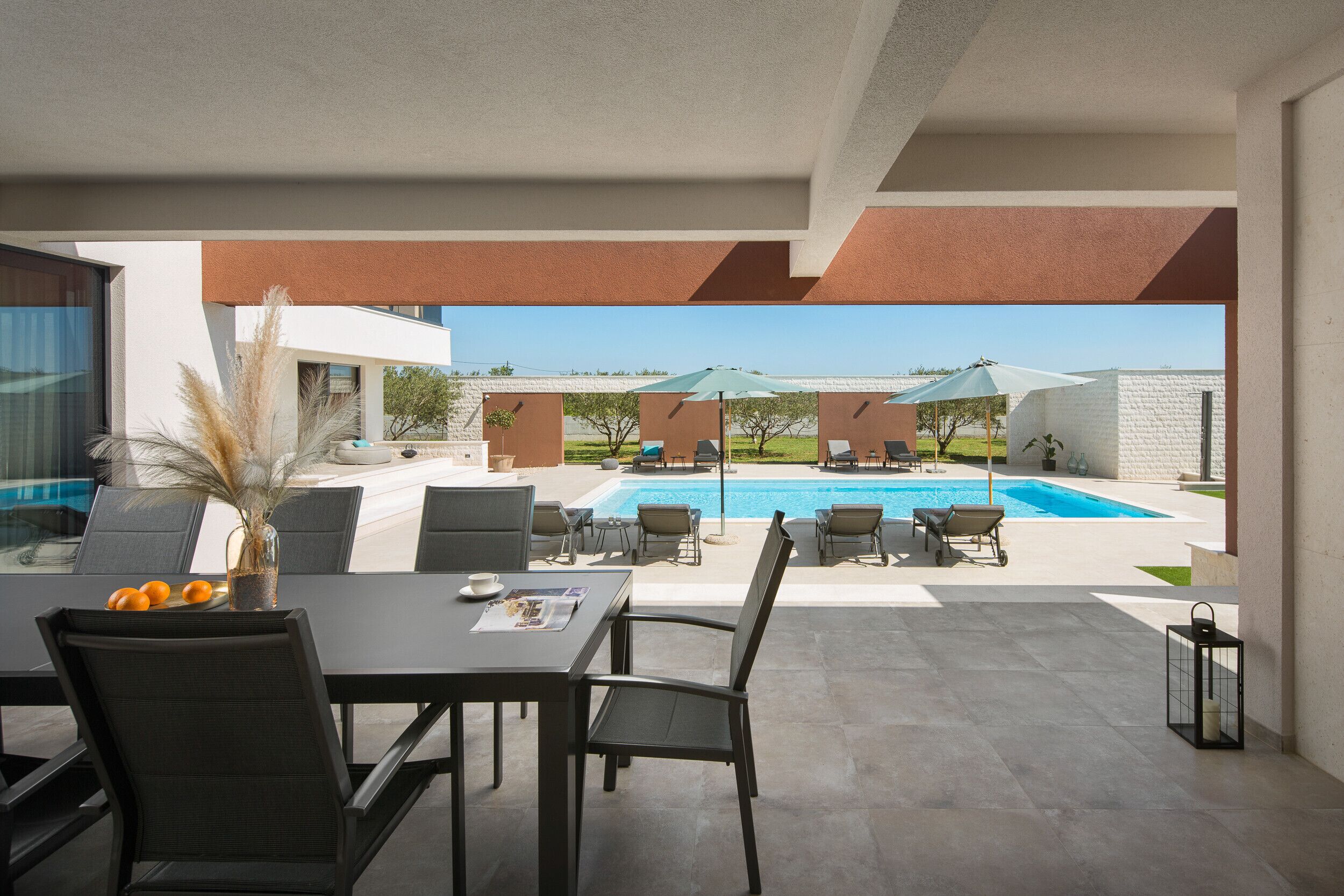 Un espace aménagé au bord de la piscine, avec une table à manger, des chaises et des parasols.