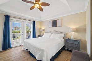 A bedroom with a bed, nightstands, a ceiling fan, and a view through a sliding glass door.