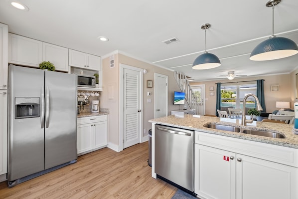 A modern kitchen with stainless steel appliances, white cabinetry, and a central island with a sink.