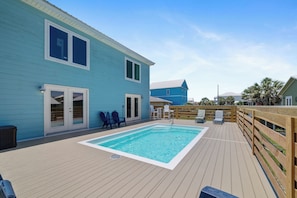 Una casa blu con veranda in legno e piscina.