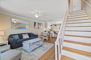 A living room with a sofa, coffee table, and a dining area with chairs and a table.