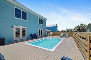 Une maison bleue avec une terrasse en bois et une piscine.
