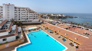 A hotel with a swimming pool, beach view, and multiple balconies.