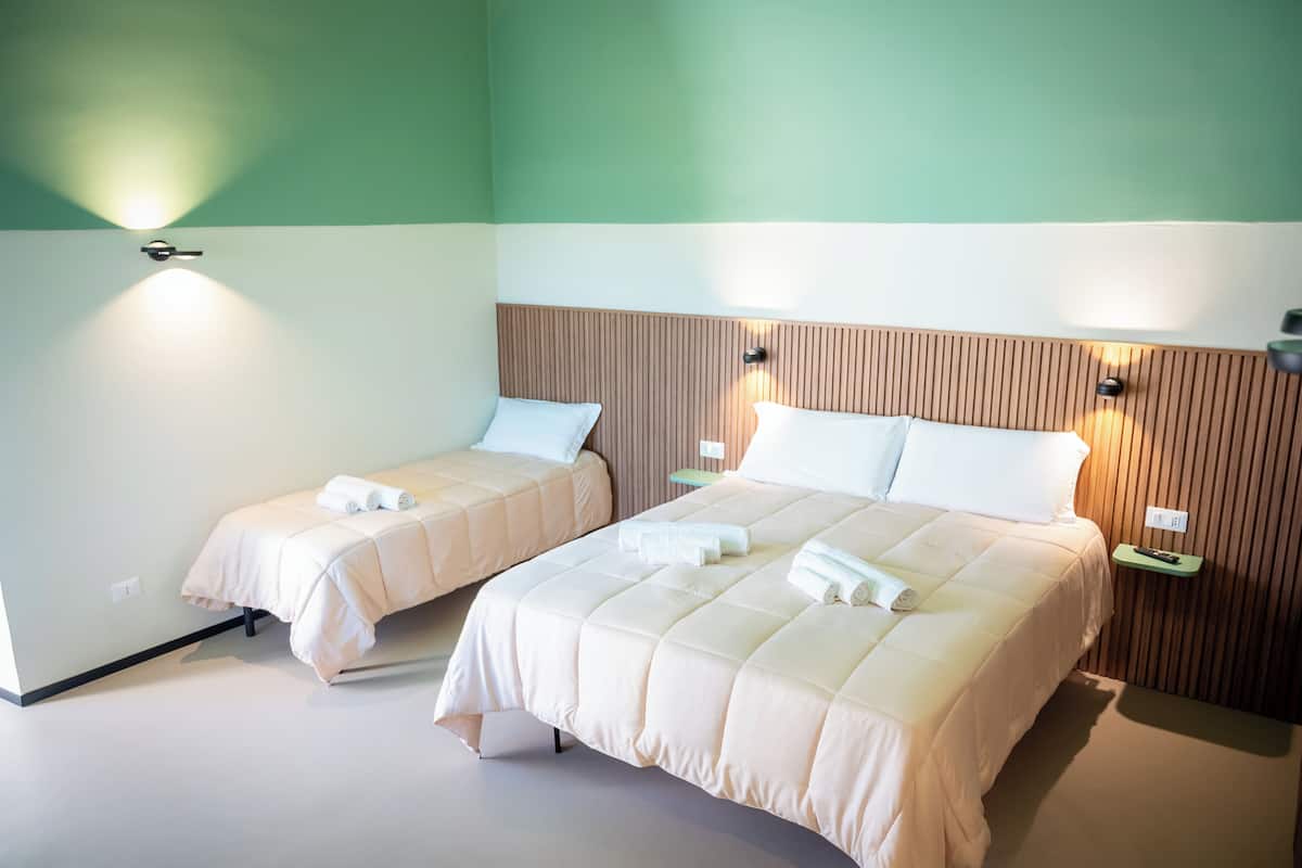 Una habitación de hotel con dos camas, cada una con una almohada y una toalla enrollada.