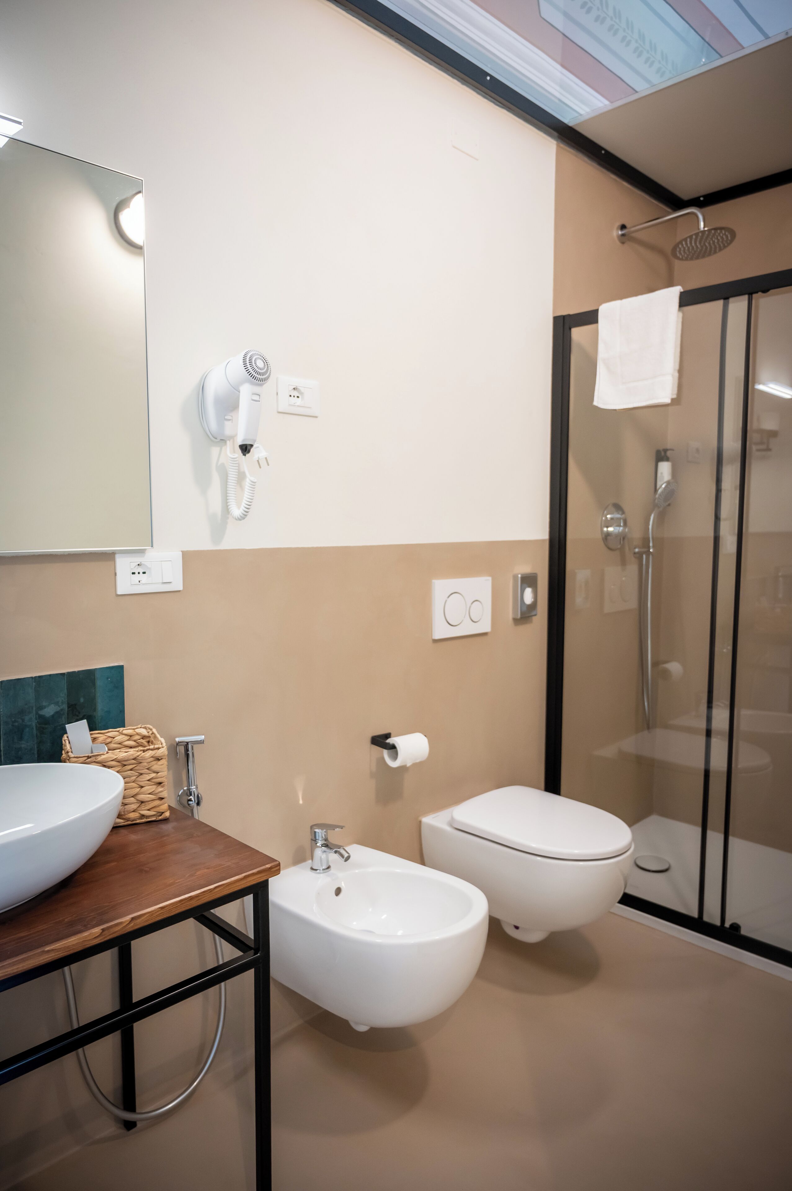 A modern bathroom with a large mirror, a vanity with a sink, a bidet, a toilet, and a glass-enclosed shower area.