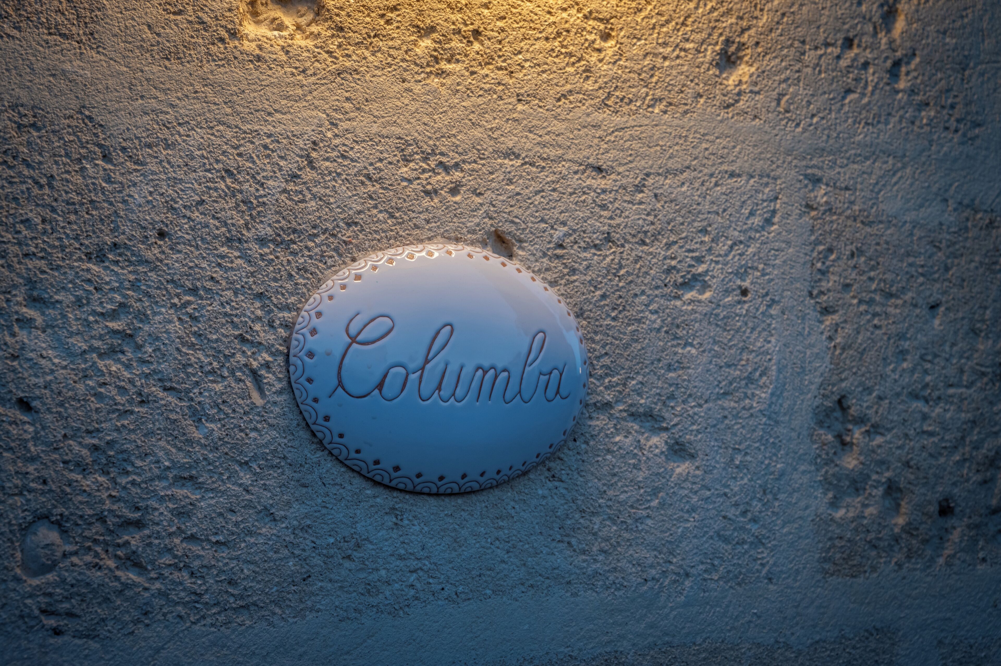 A round, white sign with "Columbia" written on it, placed on a textured surface.