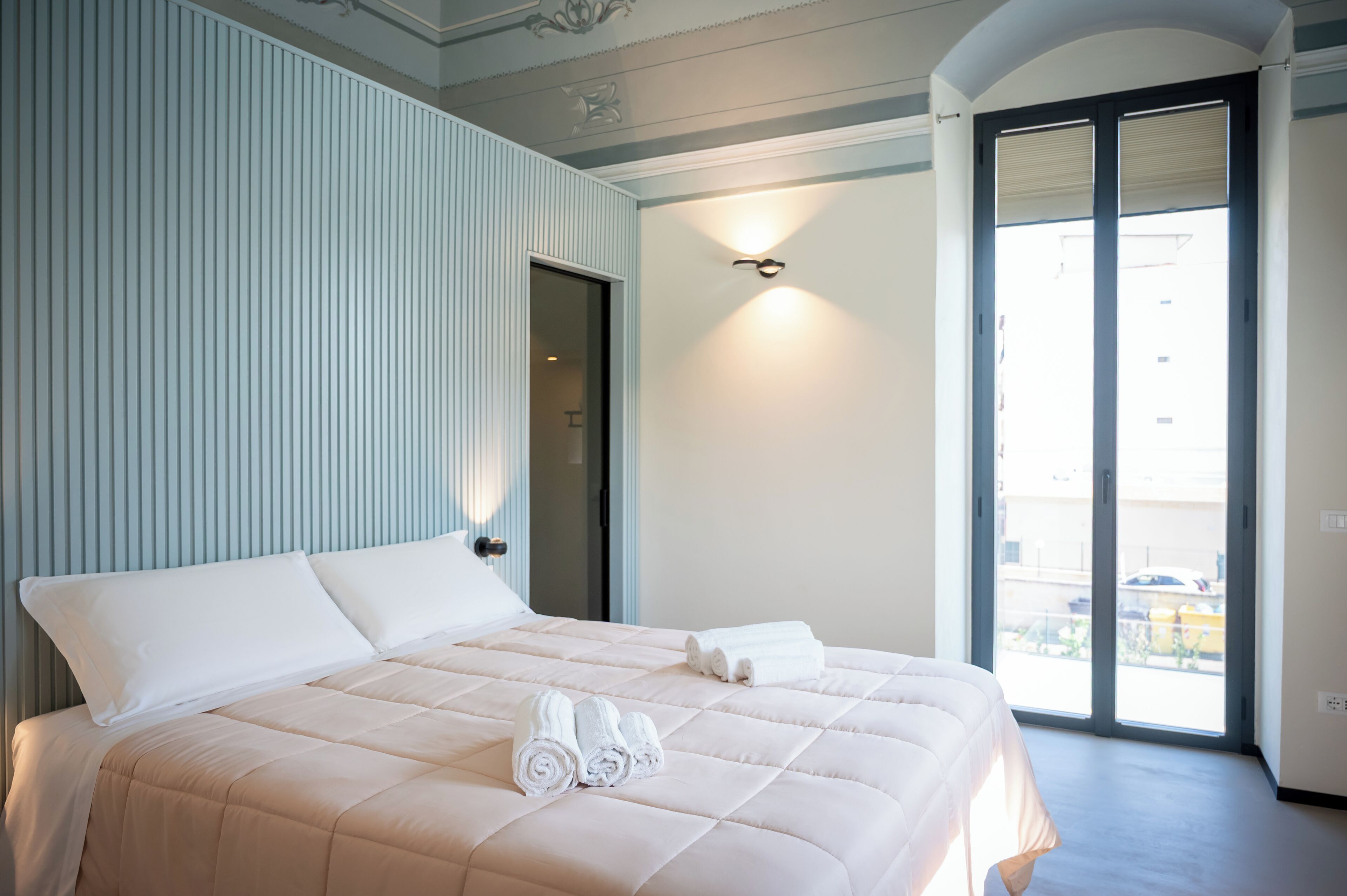 Una camera d'albergo con un letto grande, una porta che dà su un balcone e vista all'esterno.