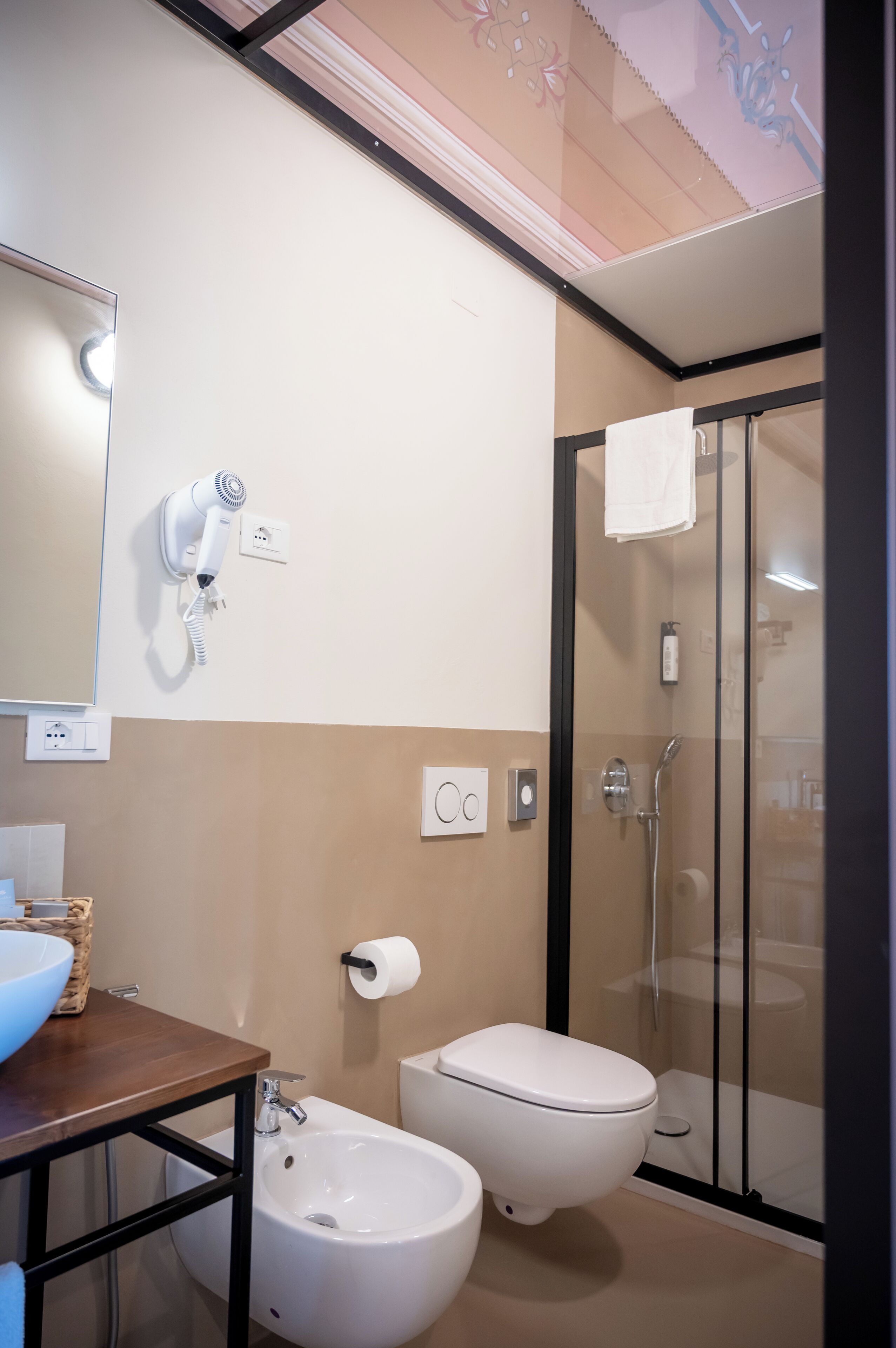 Un bagno moderno con doccia, toilette, bidet e un asciugacapelli montato a parete.