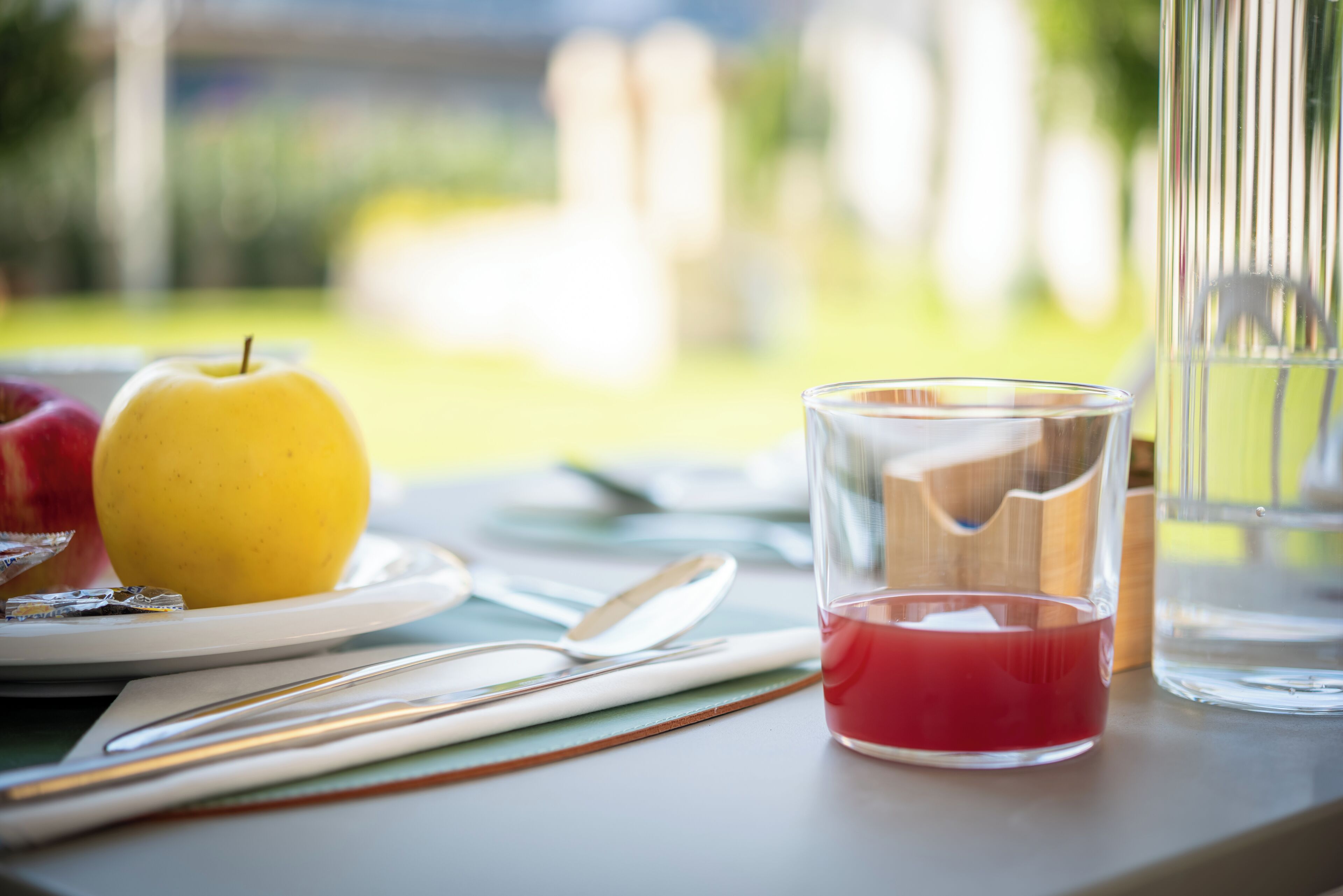 Une table avec une assiette de nourriture, un verre de boisson rouge et un verre d’eau.